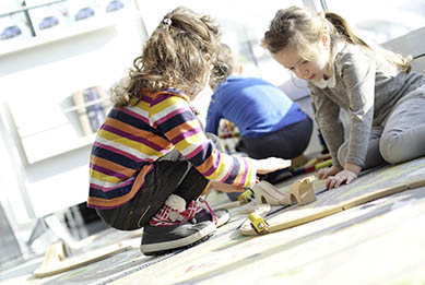 Zwei kleine Mädchen spielen auf dem Boden in lichtdurchflutetem Kindergarten